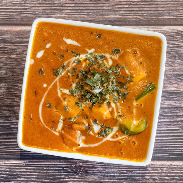 Avasa's paneer butter masala, a rich orange Indian curry with paneer, cream swirls, and herbs.
