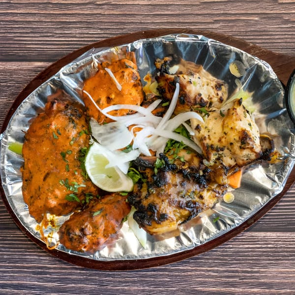 Avasa's Indian chicken platter with tandoori and grilled chicken, onions, and lime on foil.