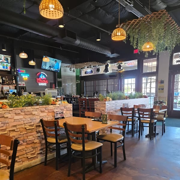 Interior of Avasa restaurant with wooden tables, chairs, stone planters, and hanging wicker lights.